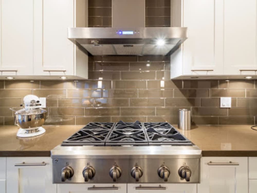 A stainless steel extractor hood above a range cooker in a domestic kitchen.