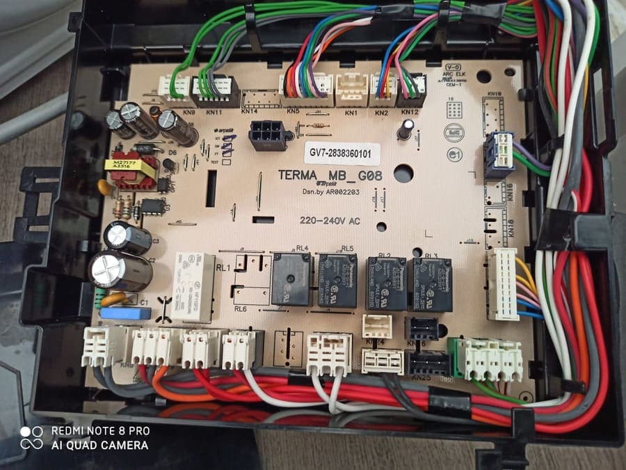 An appliance control board removed from its housing, with the loom still connected.